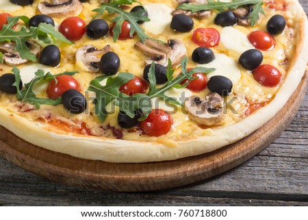 Italian pizza with mozzarella , tomato , olives and mushrooms arugula