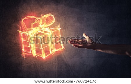 Glowing fire gift box icon in palm on dark background