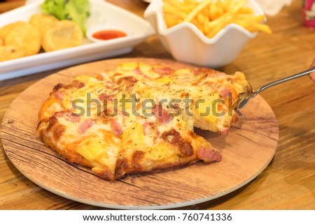 Ham and pineapple pizza on a cutting board detail. pizza put on wooden plate, eating hawaiian pizza.