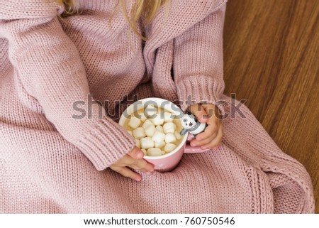 children hand in pink knitted sweater and 
holding a cup of coffee