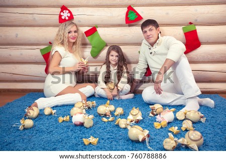 Beautiful family in Christmas interior, pregnancy, in a wooden house