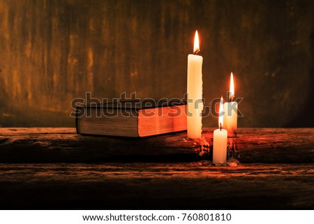 Bible and candle on a old oak wooden table.  Beautiful gold background.Religion concept.