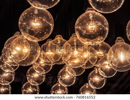 Vintage glowing light bulb hanging from the ceiling on the black background