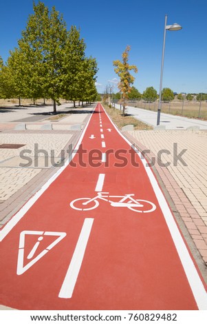 red bike double lane with painted white signs, cycle icon, warning triangle and direction signs, in wide sidewalk urban street in Valdeluz town, near Guadalajara city, Spain, Europe