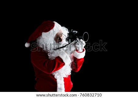 Santa claus taking picture with his camera isolated on black