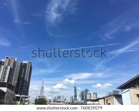 Cloud from jet engine of the plane  on blue sky with cityscape view, air transportation, you can see a little plane under the cloud but too small