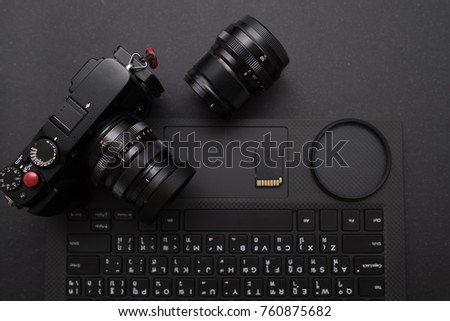 Photographer work desk, Digital camera, lens, SD card, Lens filter and laptop on black desk