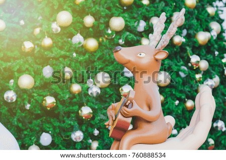 Reindeer model plays a guitar with a Christmas background.