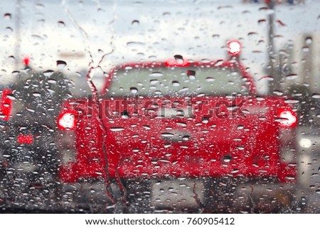 Raindrops on the windshield and a red truck in blurred background, street lights on a rainy day.