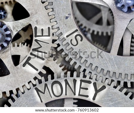 Macro photo of tooth wheel mechanism with TIME IS MONEY words imprinted on metal surface