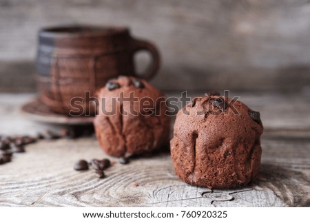 chocolate muffins and a large ceramic mug of coffee on old wooden boards