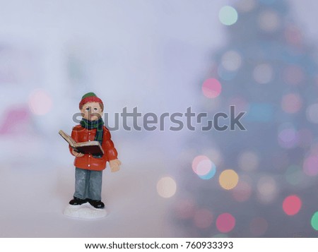 little boy figure reading book with blurry Christmas lights background, filtered tones