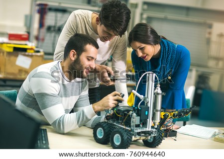 Young students of robotics preparing robot for testing in workshop Royalty-Free Stock Photo #760944640