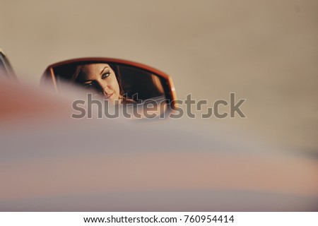 Portrait of a young beautiful girl in a car mirror reflection. she sits in an expensive prestigious car
