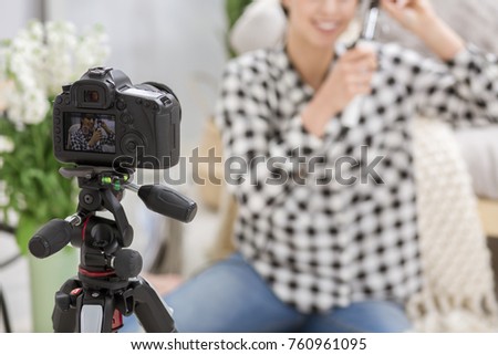 Photo of black video camera in the foreground and blogger in the background