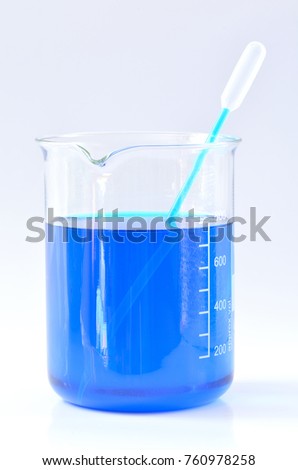 Glass chemical beaker with blue chemicals dissolved in water and laboraty pipette isolated on white background