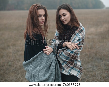 Two pretty women are standing on the field. Fall