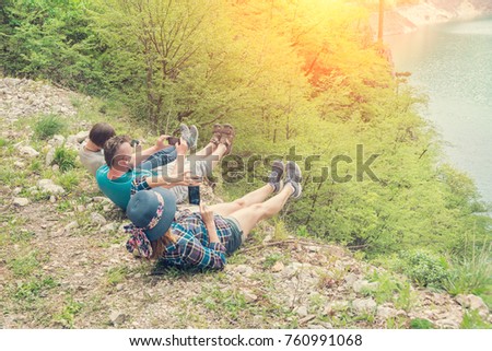 Group of people photograph their feet at the edge of the mountain
