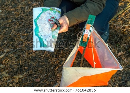 Orienteering. Compass, map, checkpoint Prism and composter for orienteering in the forest on fallen autumn needles. The concept. Royalty-Free Stock Photo #761042836