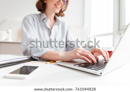 Cropped photo of pretty brunette woman typing email on laptop computer while sitting at home, selective focus on hand Royalty-Free Stock Photo #761044828