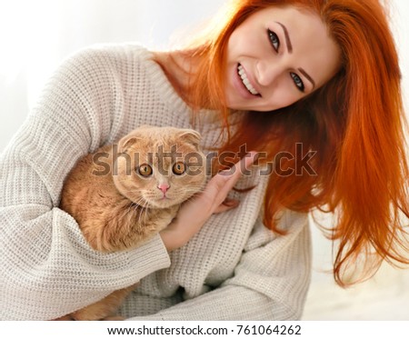 Beautiful young woman with red cat. Domestic cat Scottish Fold close-up.