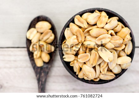 Peanuts in a white cup rests on an old wooden floor. Royalty-Free Stock Photo #761082724