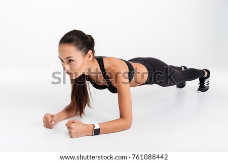 Portrait of a concentrated asian fitness woman doing plank exercise isolated over white background