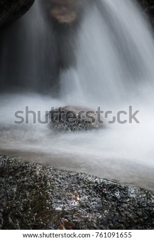 beautiful macro close up on river brook stones with satin soft waterfall flowing around, creative background
