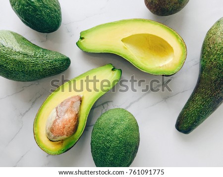 Halved avocados on a marble background, top view