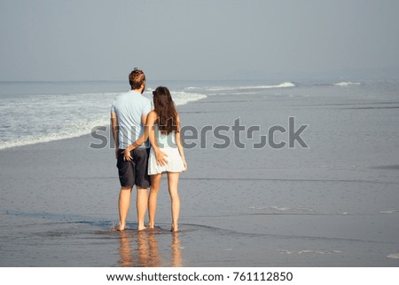 beautiful couple walking on beach view from back