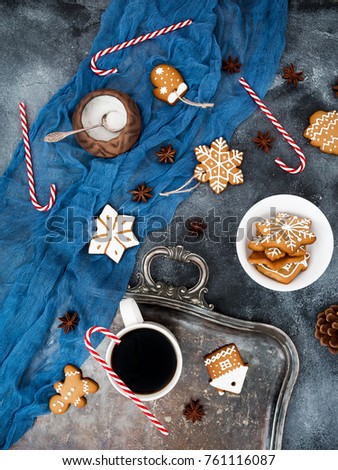 Christmas or New year composition with gingerbread, candy cane and coffee cup on dark background. Flat lay. Top view