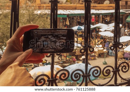 A female tourist taking a picture with her smartphone of the spice market in Marrakesh, from a coffee shop, above. 