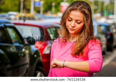 Unhappy and upset young Caucasian woman looking at her watch. Her boyfriend is late for the date.