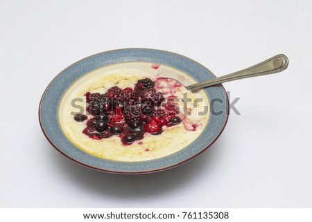 A delicious bowl of hot porridge with a forest fruit selection and drizzled with honey