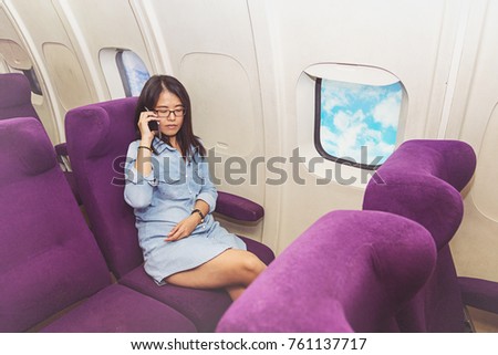Asian woman use of mobile phone inside airplane