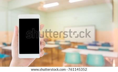 woman use mobile phone and blurred image of empty classroom
