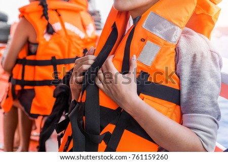 Asian female in life jacket with other people near sea on ship Royalty-Free Stock Photo #761159260