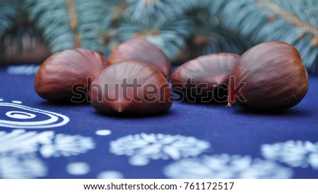 brown edible chestnuts winter christmas sweets - candies on the blue table cloth white snowflakes and bell painted on it