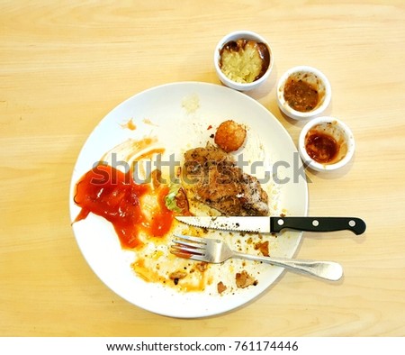 Empty dish of steak after eaten on wood table