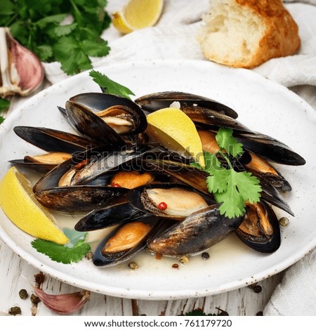 Delicious mussels in white wine with lemon, garlic, herbs and spices close up . Cilantro and pepper. Seafood. Clams in the shells. Snack for gourmets. Selective focus. Square picture