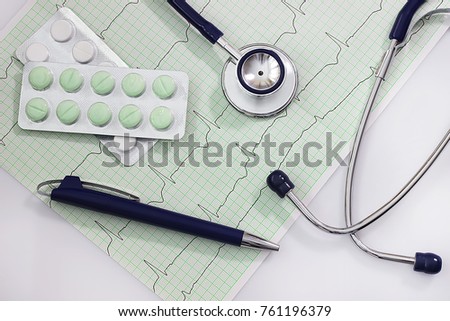 Health care concept. A stethoscope,  cardiogram and pills on a white table. 