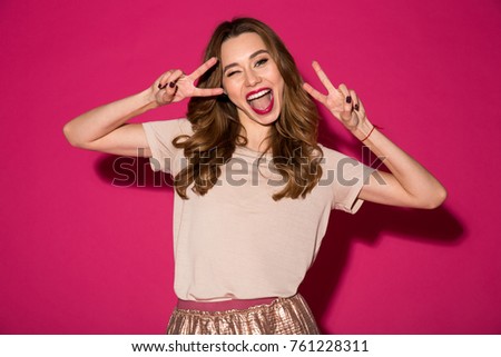 Image of happy young woman standing isolated over pink background showing peace gesture.