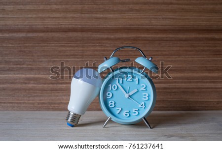 Think Fast.A bulb lean on the Blue Showing Clock on the wooden table.