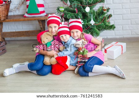 Happy kids near Xmas tree with presents near fireplace