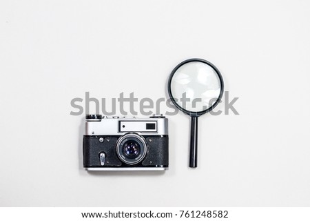 Old film camera and magnifying glass. White background close-up. Vintage photo