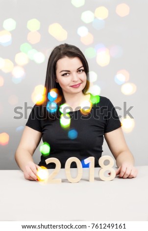 Beautiful girl posing with figures 2018. New Year's concept, postcard, poster. Blurred lights of garlands