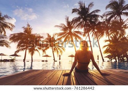 Woman enjoying vacation holidays at luxurious beachfront hotel resort with swimming pool and tropical lansdcape near the beach Royalty-Free Stock Photo #761286442