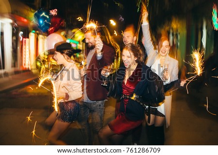 Group of happy friends going on the party, having fun at the street and drinking champagne. New year party. Birthday party