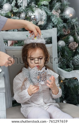 Mother putting on tiara to head of daugther during christmas celebration.