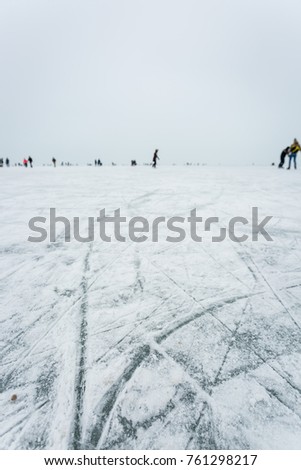 Ice skaters on lake focus on ice